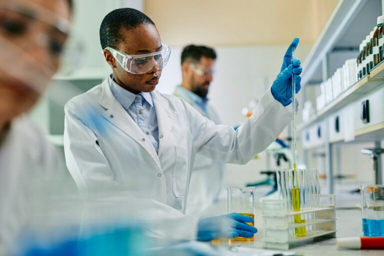 Black biotechnologist analyzing chemical samples during scientific research in a lab.