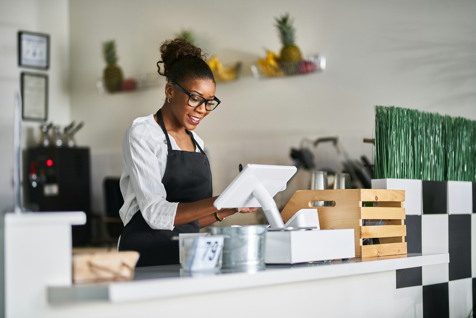 friendly african american shop assistant using pos terminal to input orders at restaurant